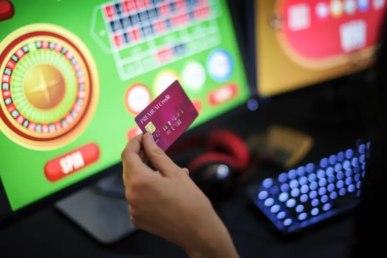Person Holding A Credit Card While Gambling Online